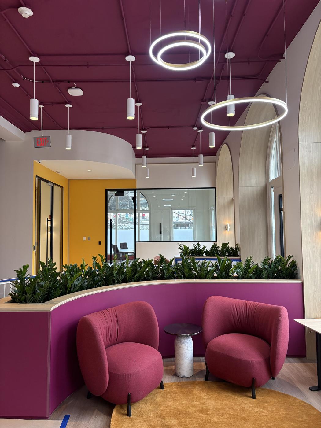 Finished lounge with a curved purple planter wall and red chairs